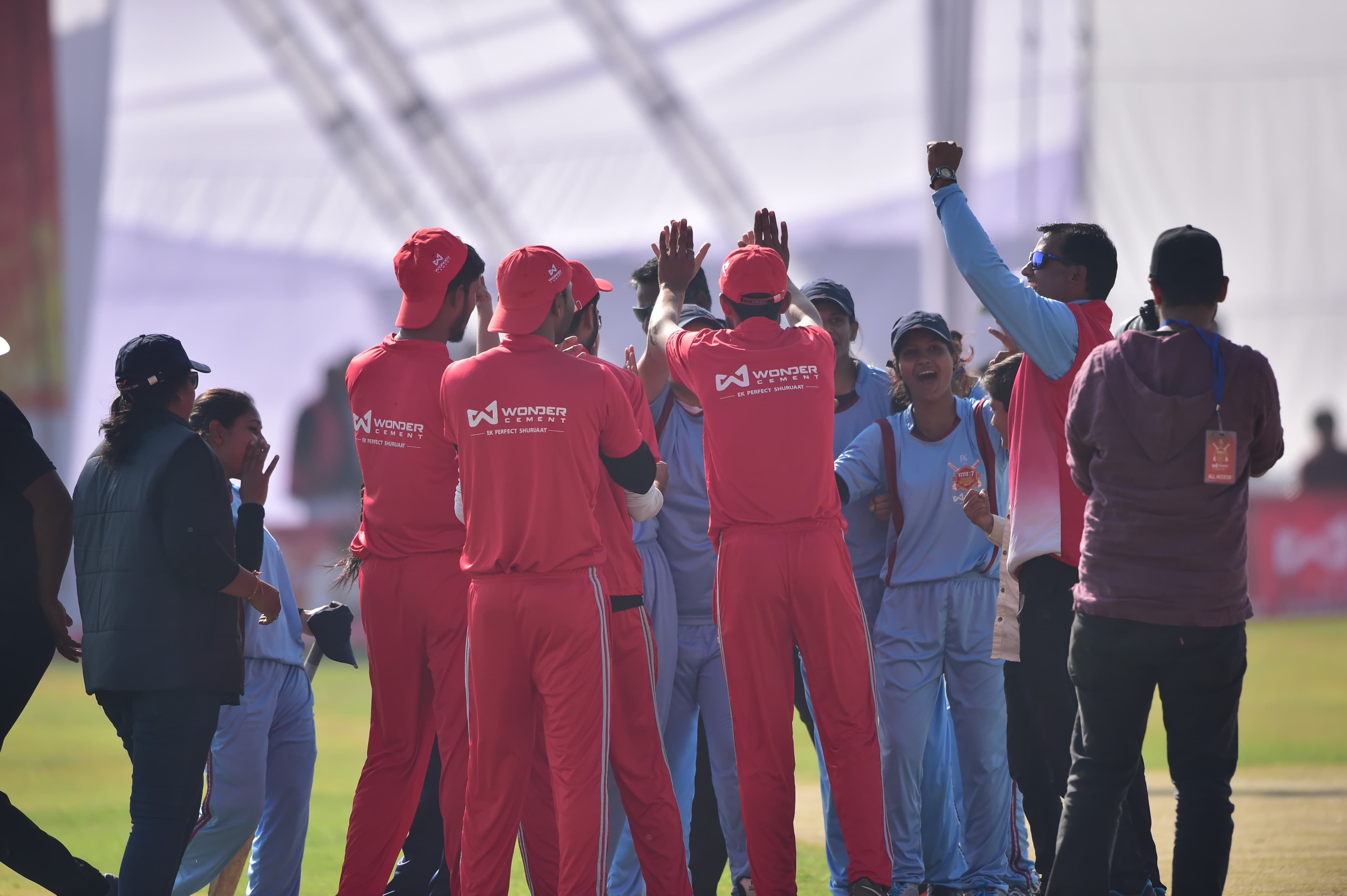 Players huddled together at a real साथ:7 Cricket Mahotsav match